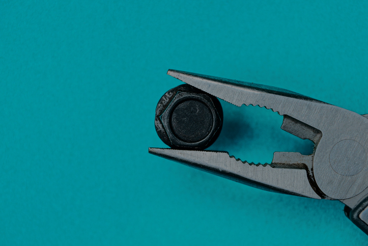Gray steel pliers holding a black bolt on a teal background represent nonprofit communications tools.